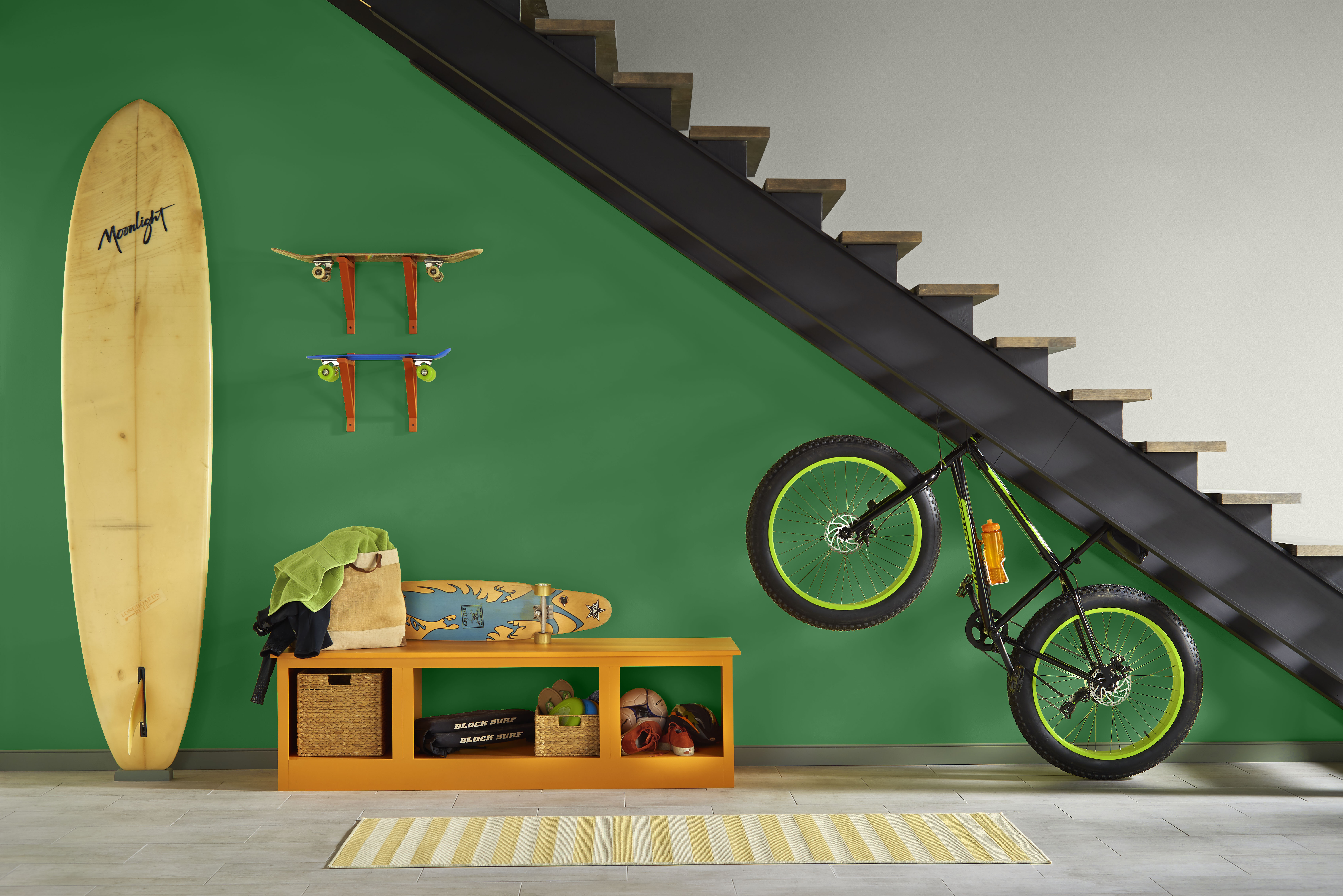 Cette image montre un espace de rangement pour les bicyclettes et les planches de surf sur fond de mur vert émeraude foncé.