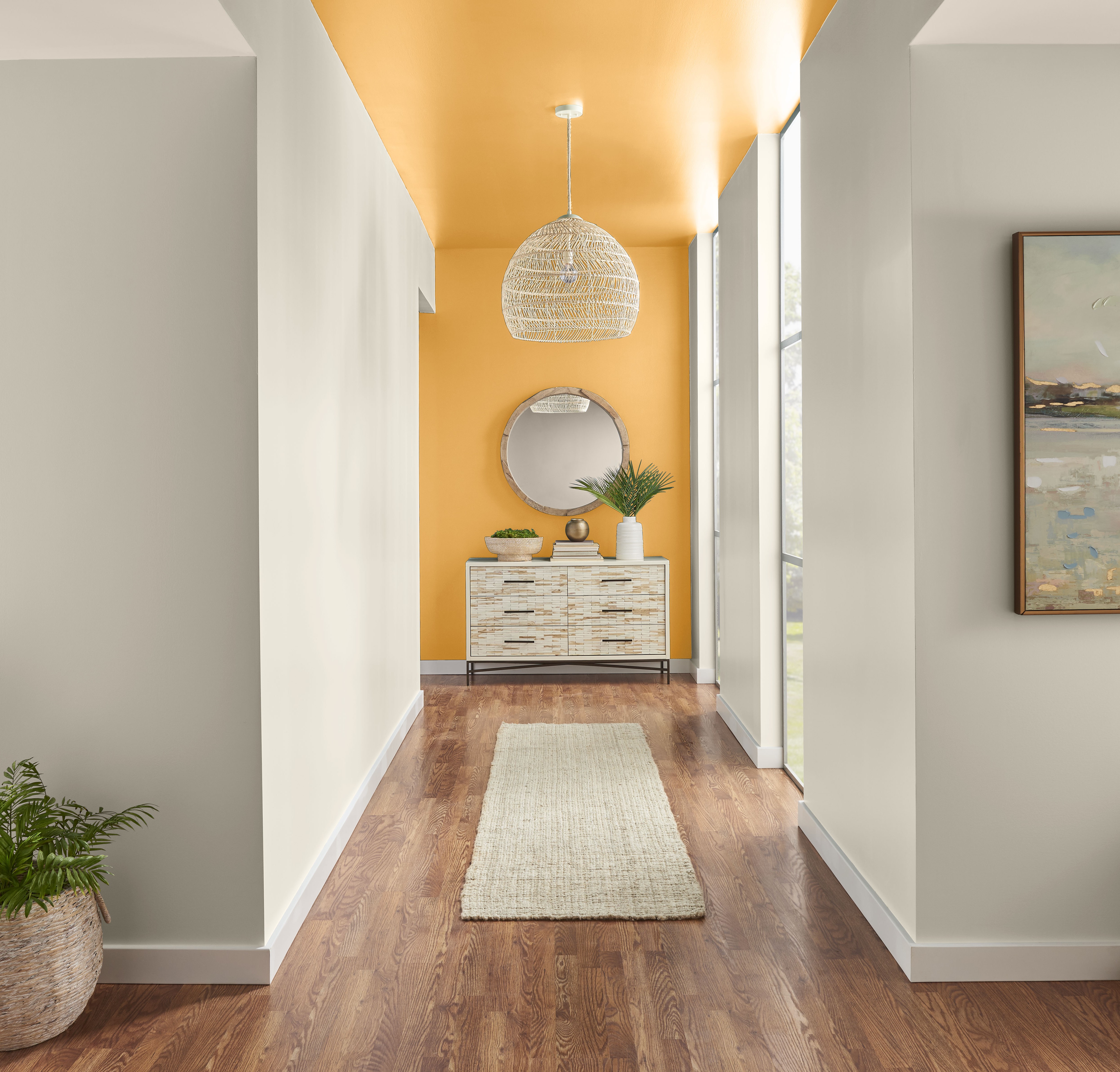 Cette image montre un couloir élégant avec un mobilier et un décor raffinés, un parquet de bois franc chaleureux, et un mur d’accent saisissant peint en Jacquier, qui ajoute une touche dynamique et moderne à cet espace sophistiqué.