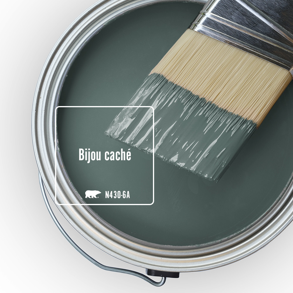 Vue du dessus d’un pot de peinture ouvert. La peinture est de couleur Bijou caché. Un pinceau à moitié trempé est posé sur le bord du pot.