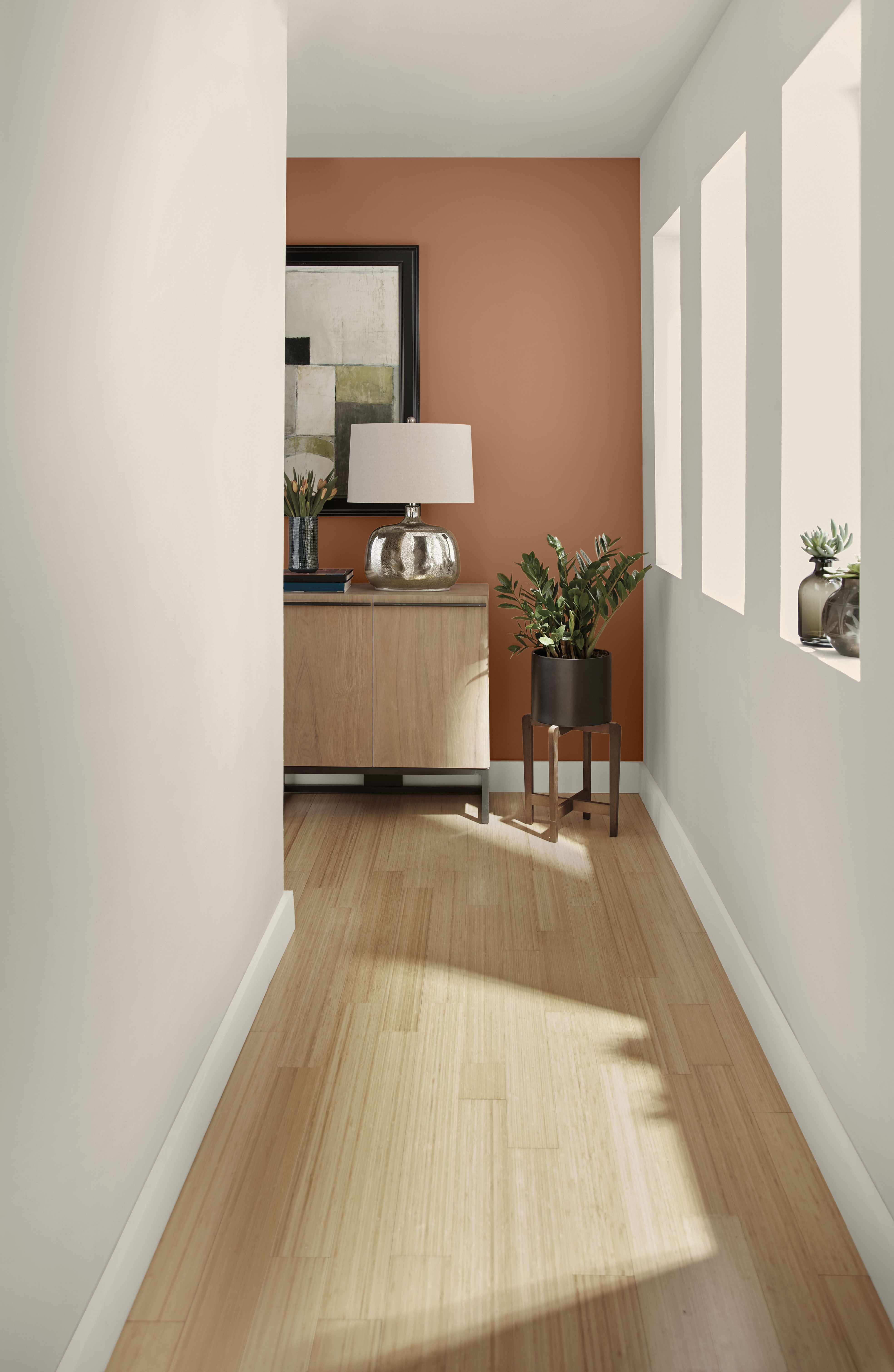 Cette image montre un couloir aux murs taupe pâle débouchant sur un autre mur peint en caramel orangé.