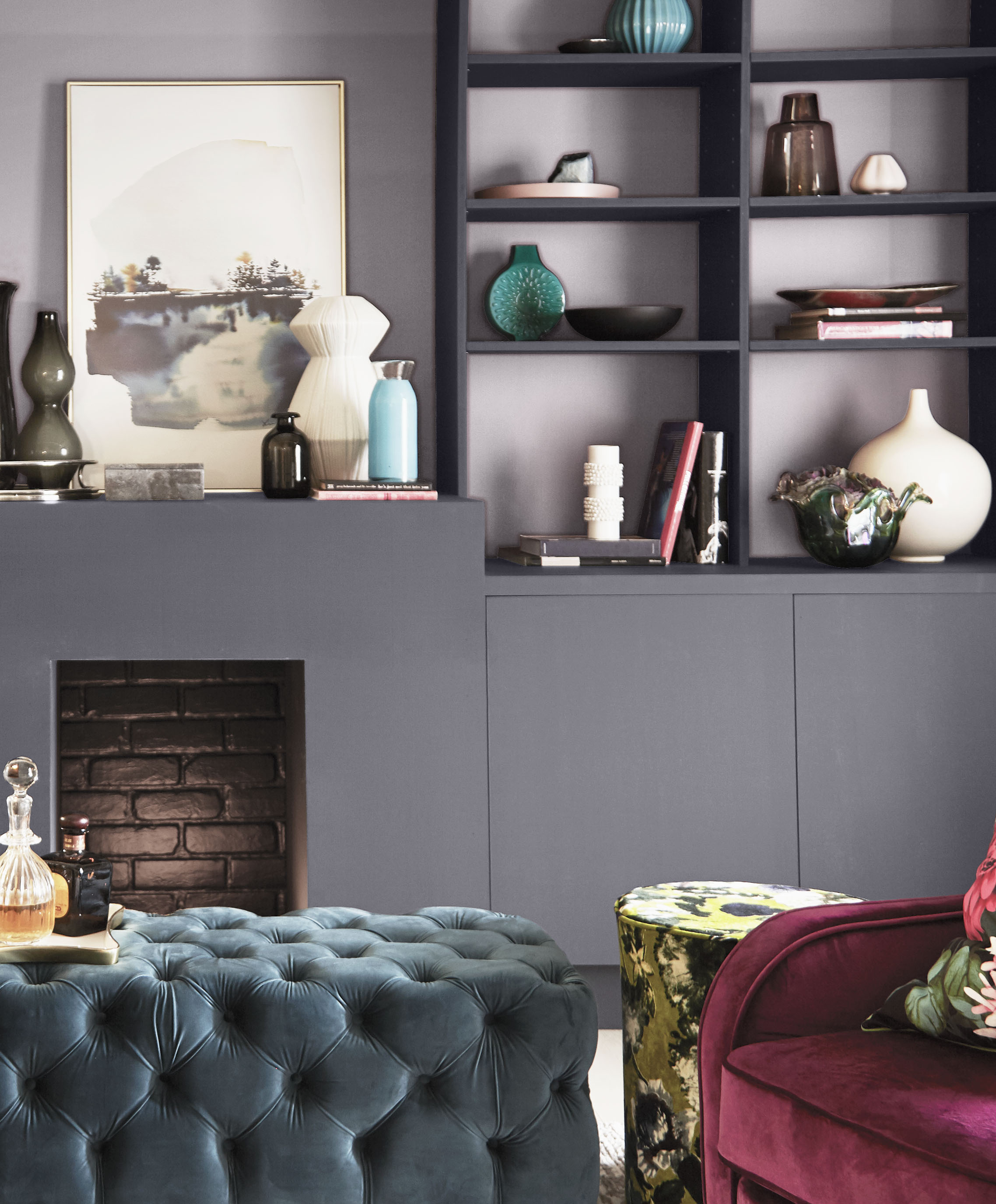 Cette image montre un salon avec une cheminée et des étagères peintes en gris acier, tandis que le mur du fond visible à travers les tablettes est peint dans une élégante teinte de gris-lavande.