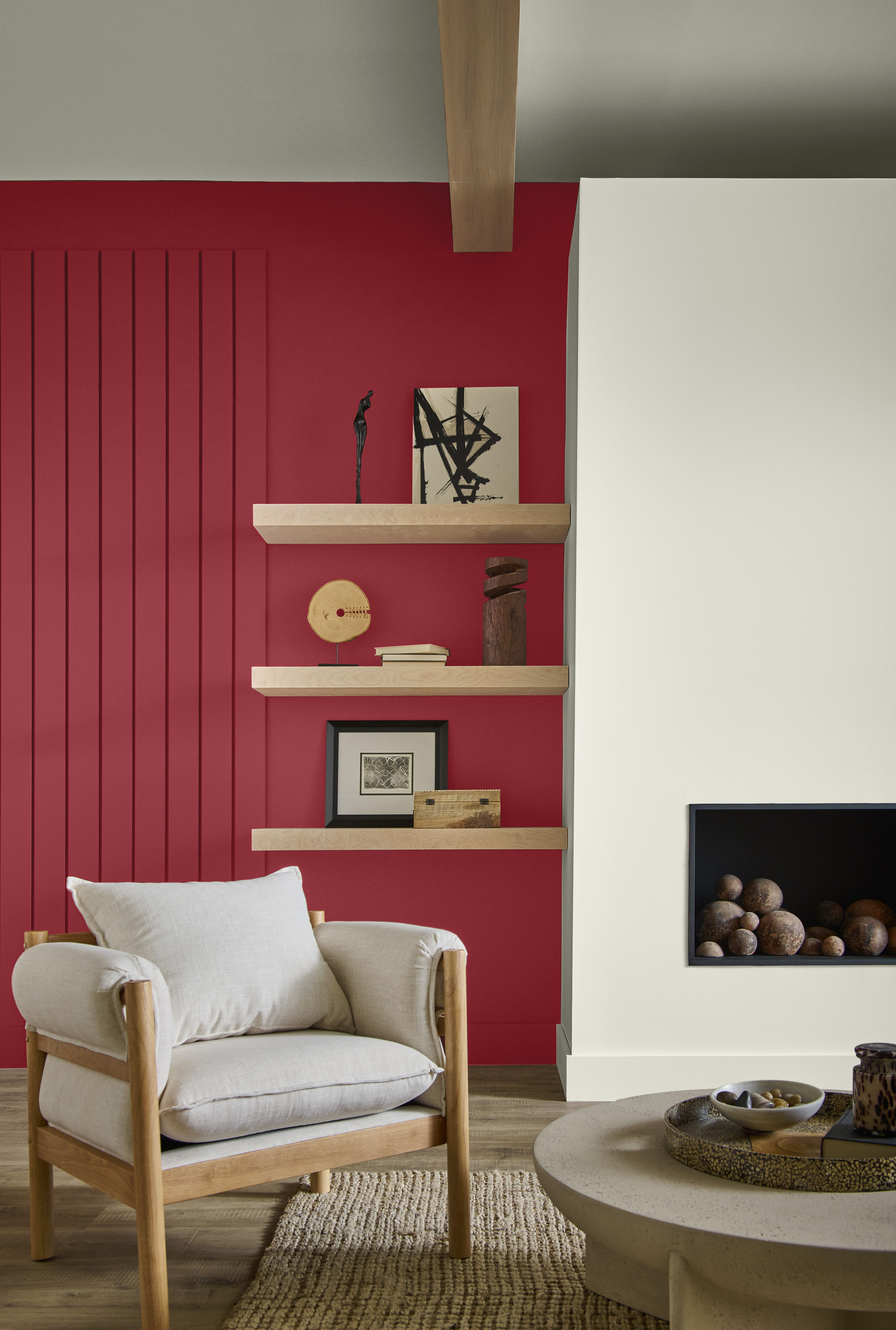 Cette image montre un coin de salon où se découpe une cheminée blanche contre un mur lambrissé peint en un rouge chaleureux.