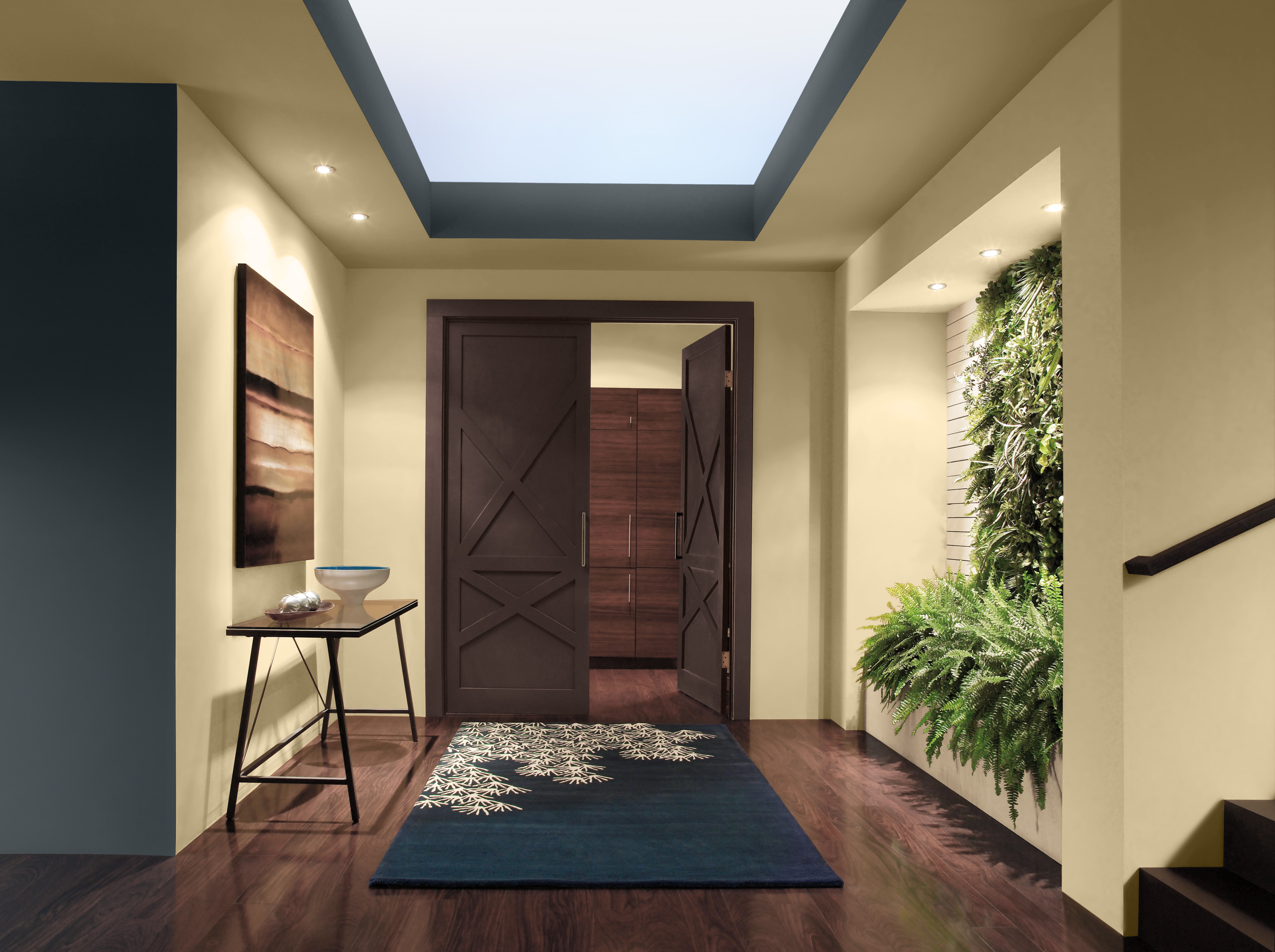 Cette image montre un vestibule dont les murs peints en un jaune chaud et lumineux sont accentués d’une teinte contrastante où se fusionnent des tons de bleu et de noir.