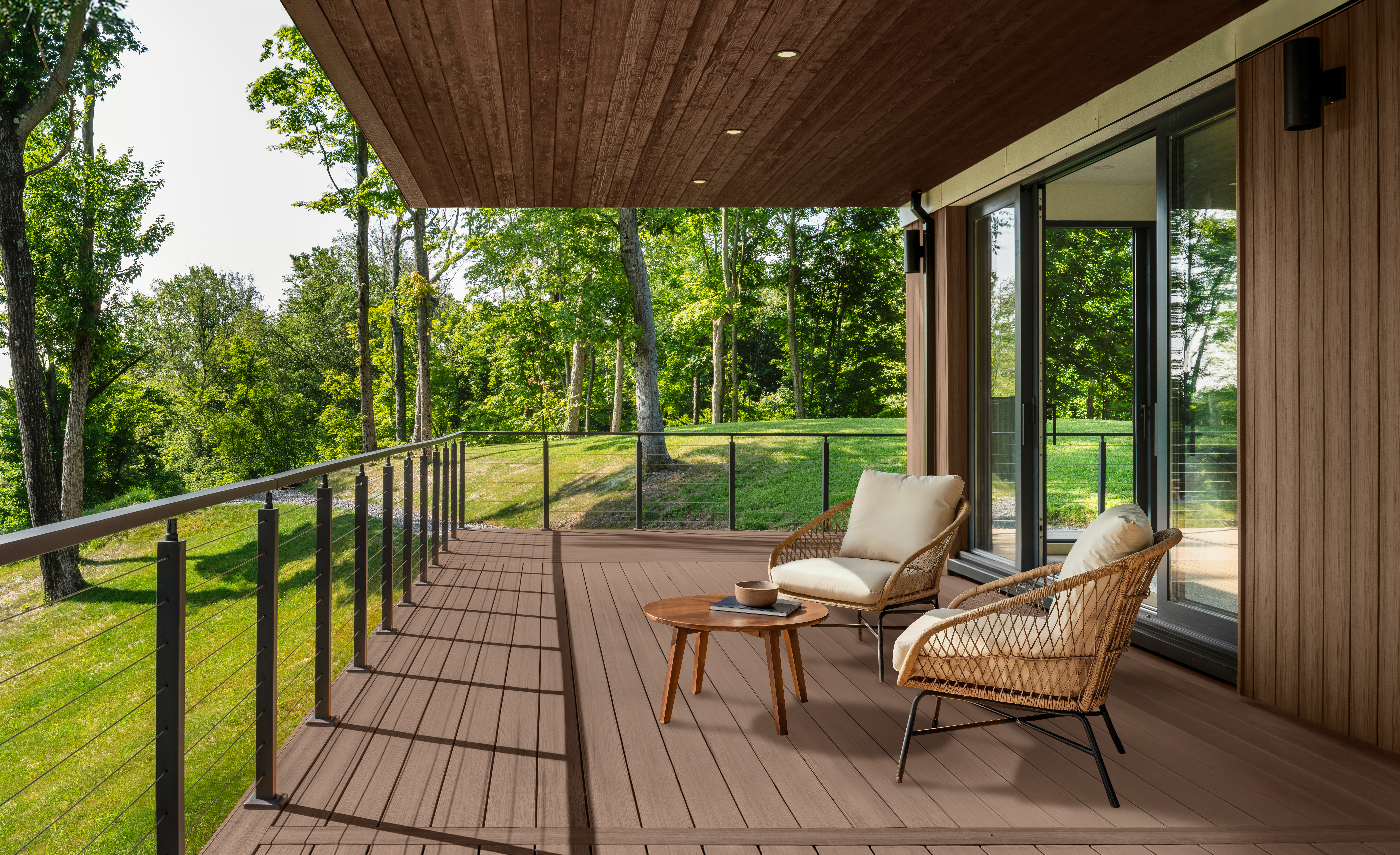 Cette image montre une terrasse extérieure couverte d’un toit en bois, avec deux nuances de teinture différentes. La terrasse est teinte en Taupe, tandis que le plafond est teint en Chocolat. La terrasse est aménagée avec deux chaises et une petite table ronde, et donne sur un paysage verdoyant parsemé d’arbres.
