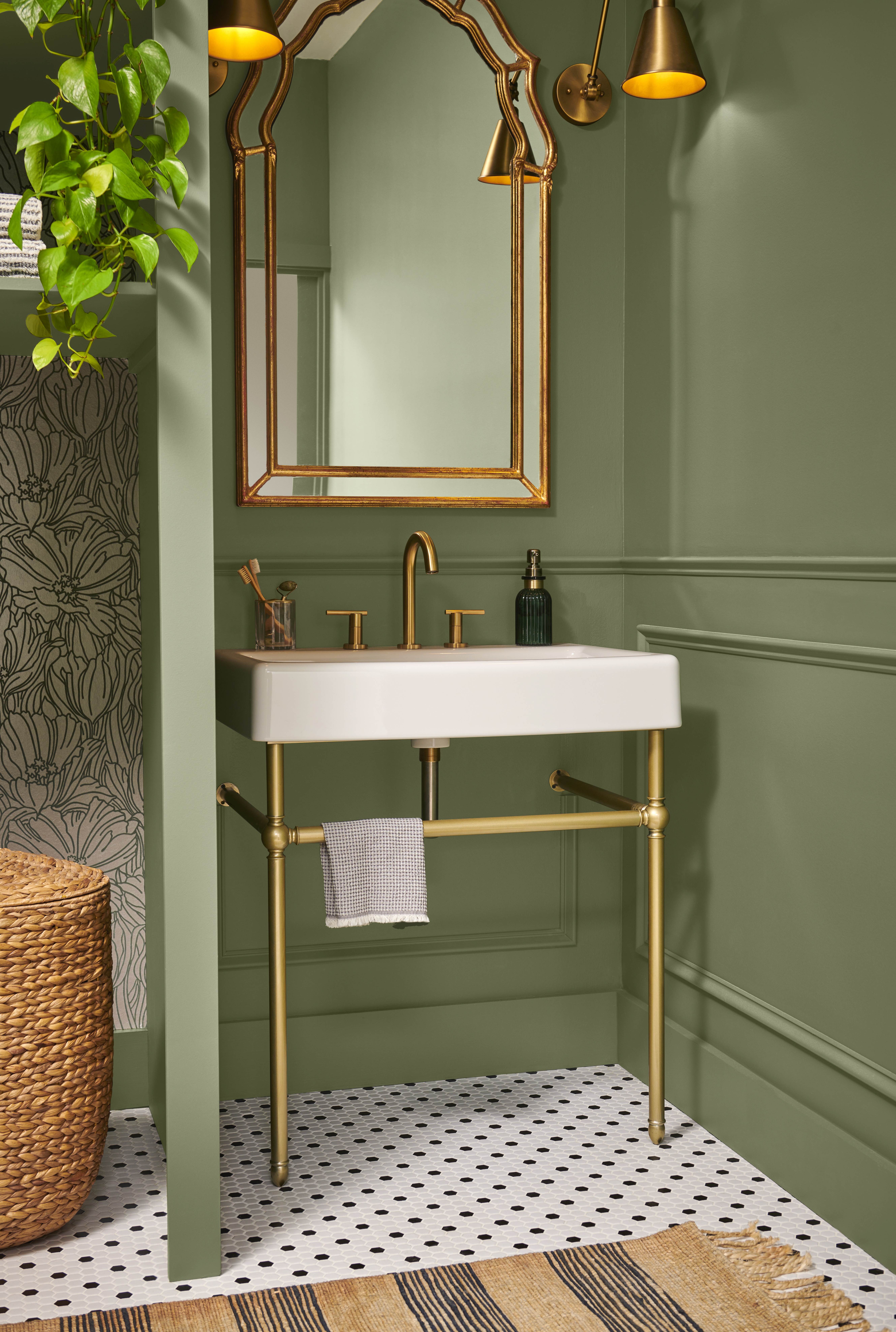 Cette image montre une petite salle d’eau aux murs peints en teinte «Écologique», équipée d’un lavabo sur pied en porcelaine blanche avec robinetterie en laiton, le tout agrémenté d’un miroir au cadre doré et de touches décoratives chaleureuses et modernes.