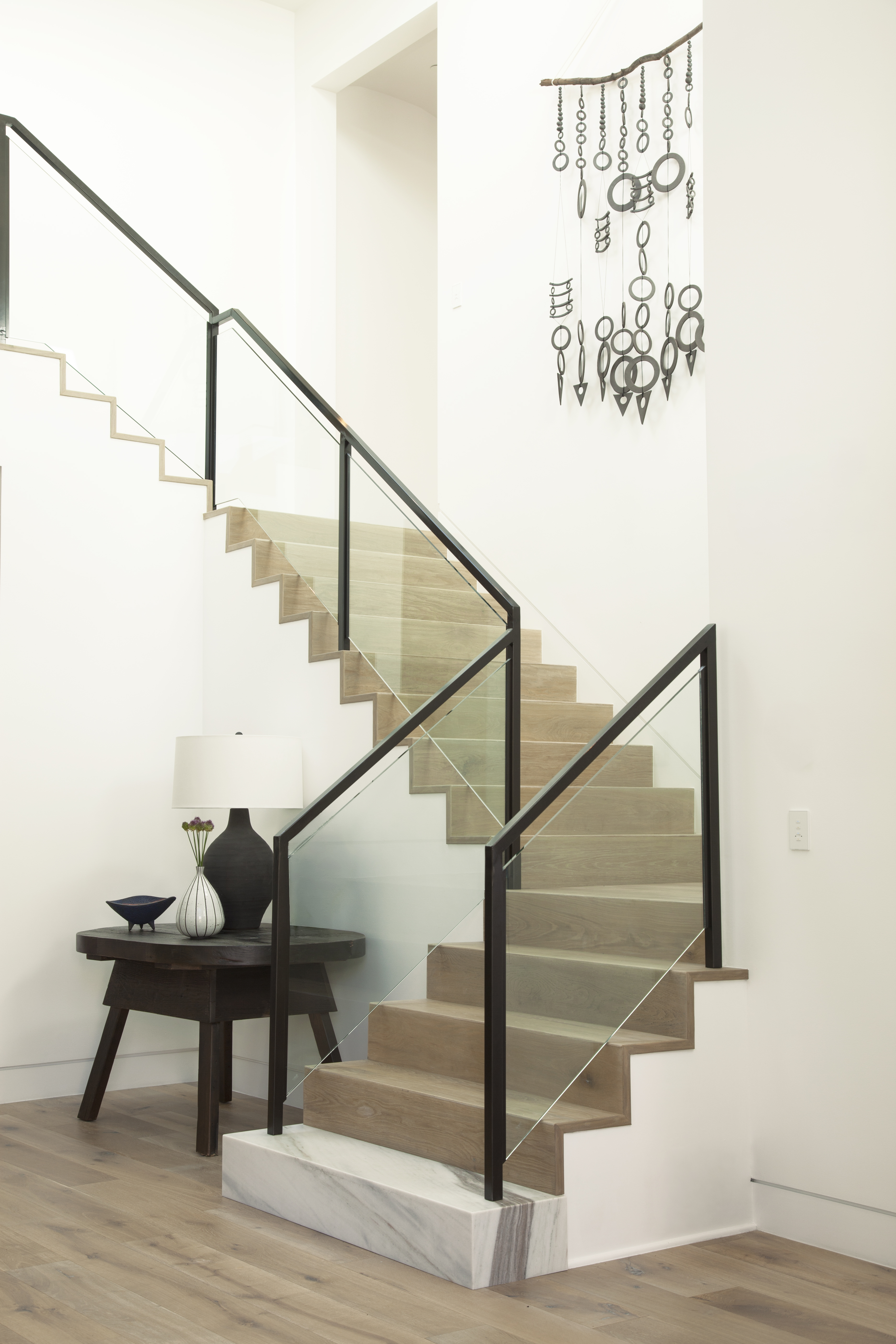 Cette image montre un escalier dont les murs sont peints en Lumières scintillantes (M280-1), un beau blanc au ton chaud, avec des marches en bois blond sur fond de décor neutre et aéré.