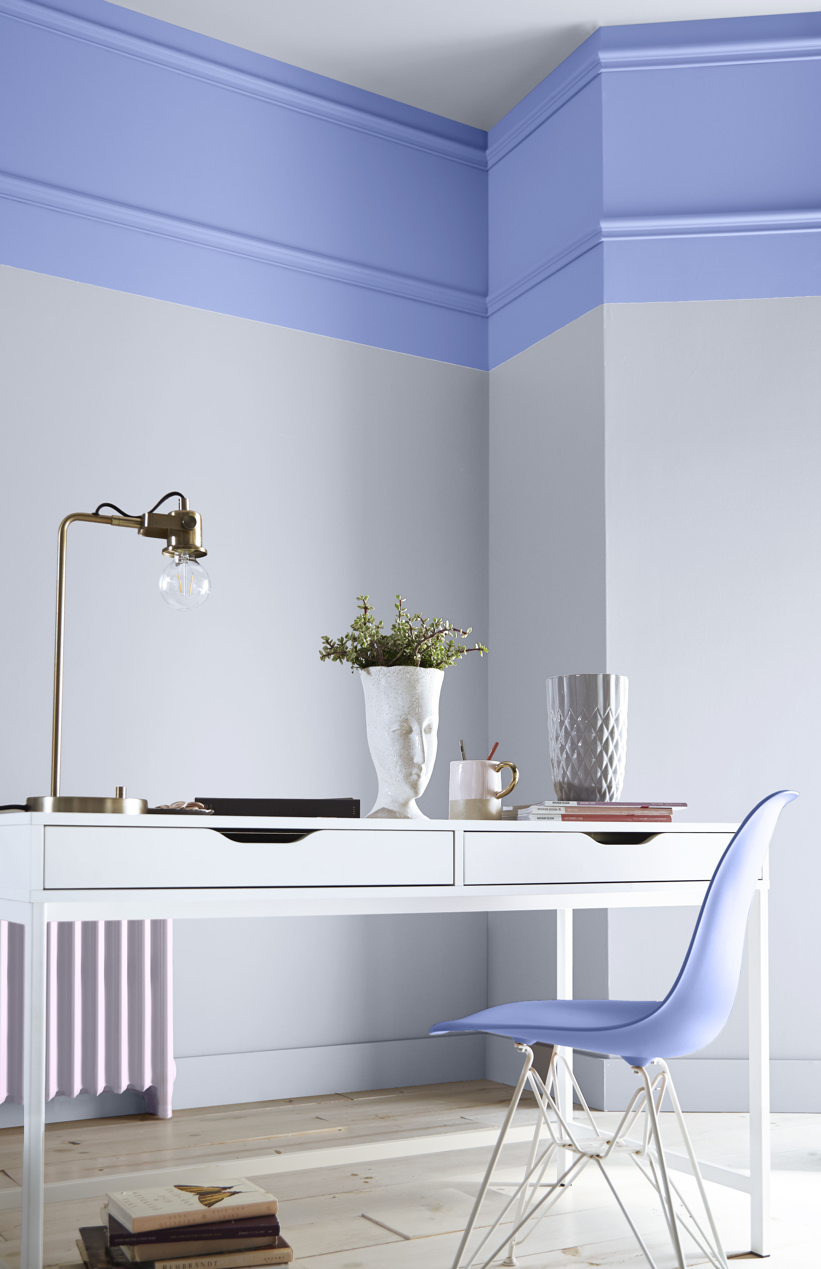Cette image montre un espace de création dont les murs peints en Ciel lavande (P540-4), un joli bleu-violet, complémentent à merveille la table blanche et les accessoires aux teintes pastel plus douces.