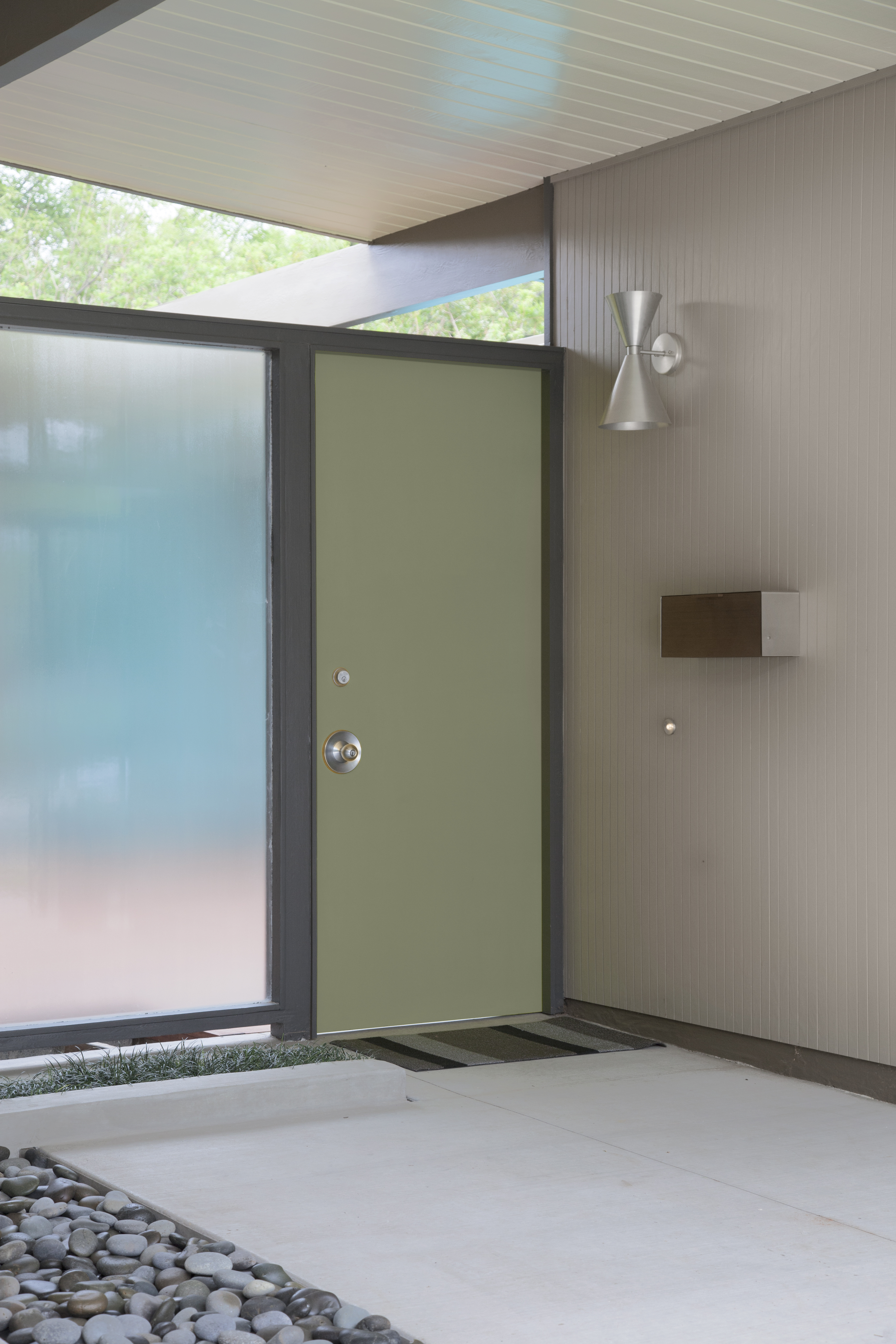 Cette image montre l’entrée d’une maison moderne de style milieu du siècle, avec une porte verte, un panneau en verre givré, un bardage brun pâle et une allée en béton.