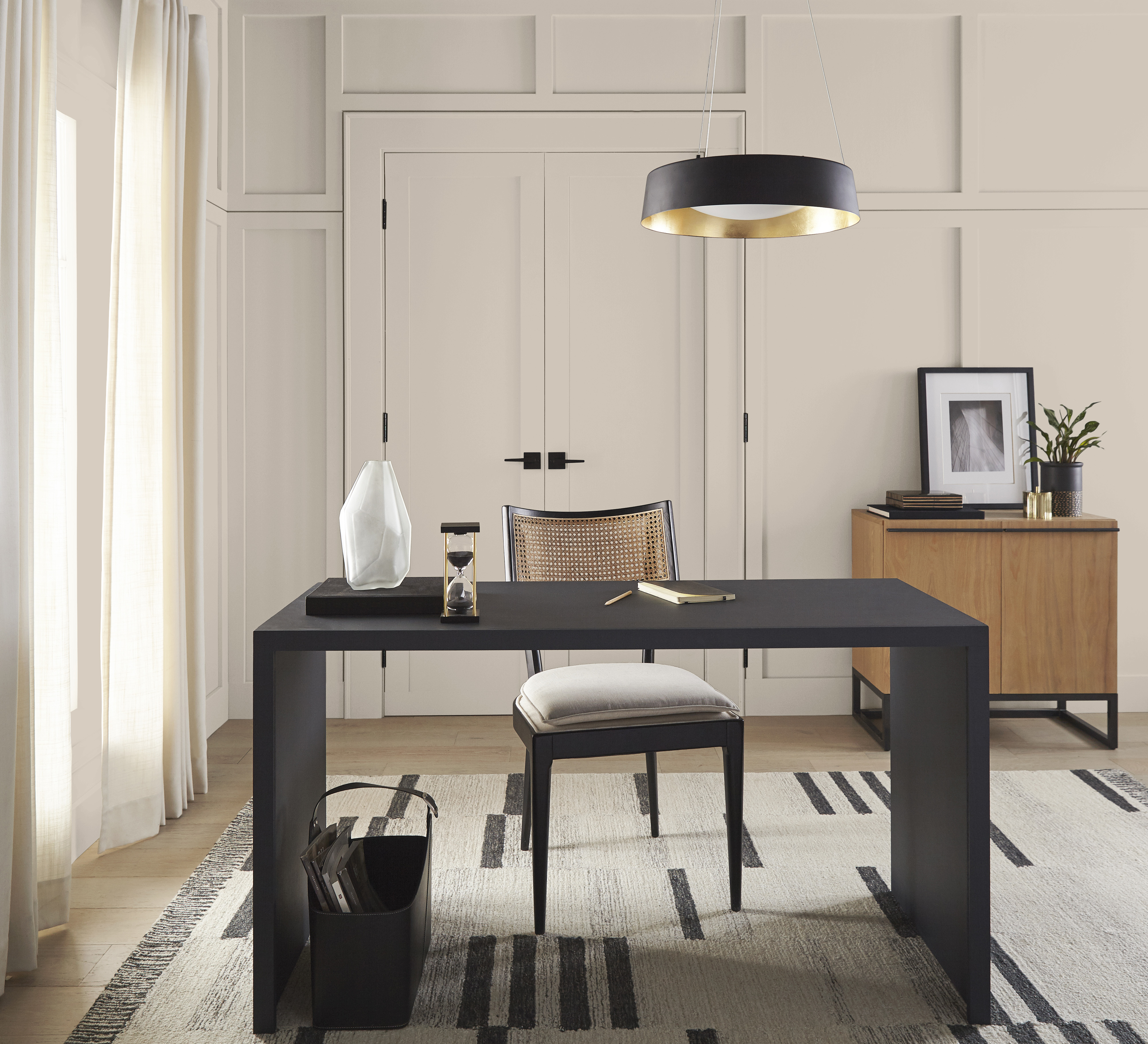 Cette image montre un espace de télétravail où un bureau et une chaise noir ébène créent un élégant contraste contre les murs Pain de blé, et où la superposition de textures naturelles apporte de la profondeur et du relief. La pièce dégage une ambiance à la fois sophistiquée et conviviale, alliant productivité et confort dans un décor inspirant qui joint l’utile à l’agréable.