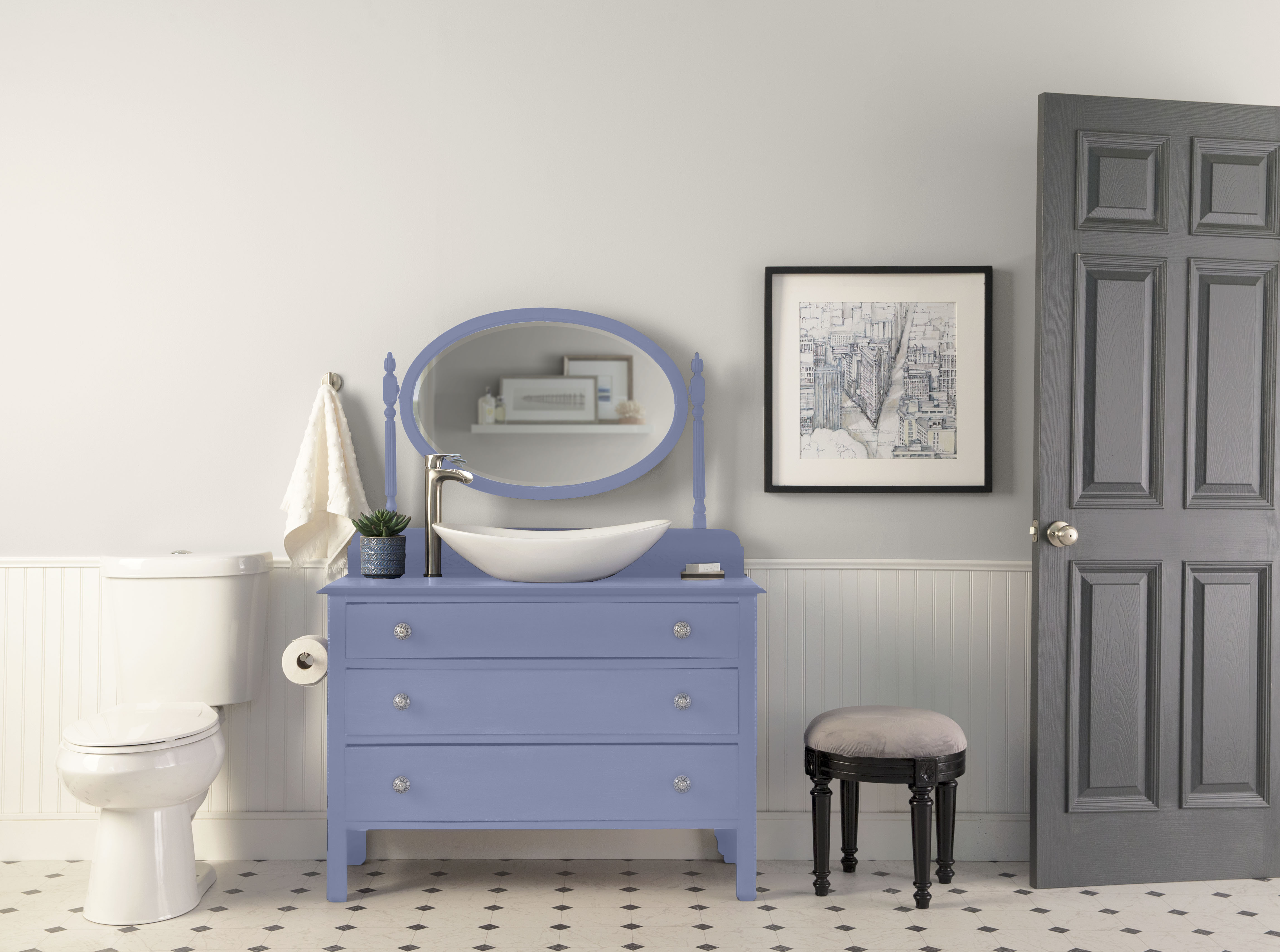 Cette image montre une salle de bain avec un demi-mur lambrissé peint en teinte Blanc camée et surmonté d’un demi-mur pâle de couleur neutre, ainsi qu’un meuble-lavabo bleu peint en Ruban vintage, une porte grise, un carrelage à motifs et des accessoires d’inspiration ancienne, le tout créant un élégant décor romantique.
