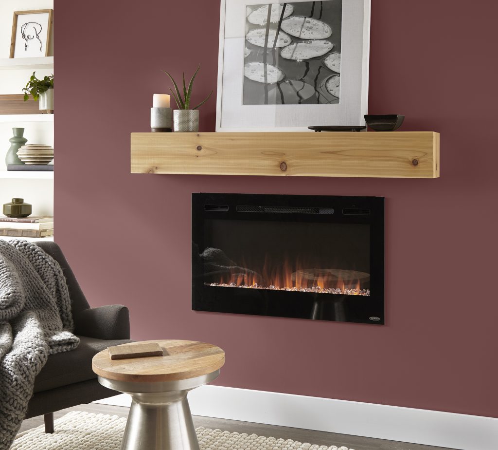 Cette image montre un mur de salon peint en teinte Double baie (MQ1-14), avec une allège de cheminée en bois naturel qui surplombe un foyer encastré noir, ainsi qu’un mobilier aux couleurs neutres, des petites plantes d’intérieur et un jeté en fausse fourrure gris pâle.