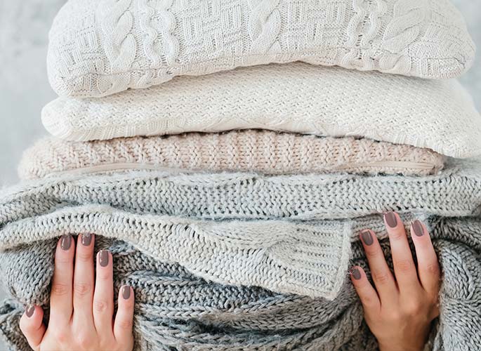 A stack of warm, cozy neutral colored sweaters.