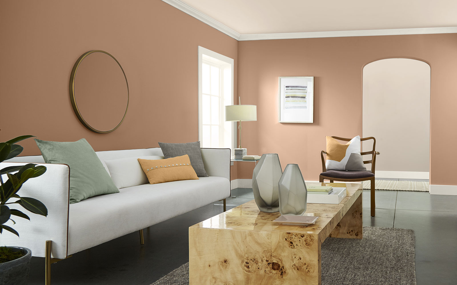 A living room image with four color swatches sitting beside it. The image displays the four colors: a light, but bright clean orange hue for a pillow  on the couch, a dusty orange hue is used on the wall, a creamy white hue is used for the trim, ceiling and couch, and a minty green is used for a pillow.